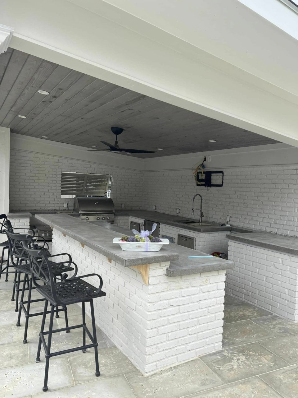 An outdoor kitchen with a bar and stools.
