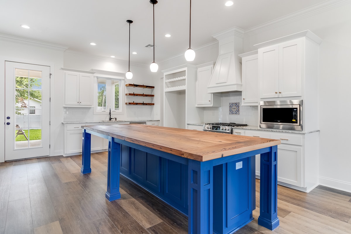 A kitchen with a blue island and white cabinets.
