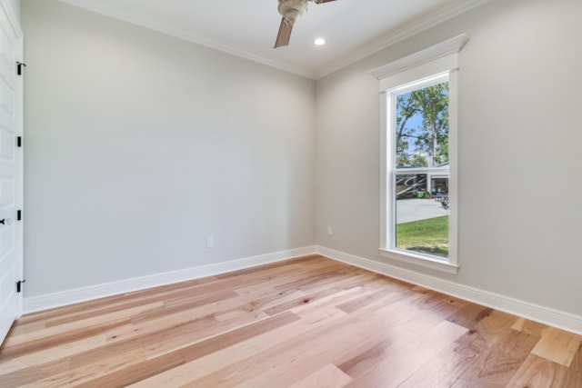 an empty room with wood floors and a ceiling fan.