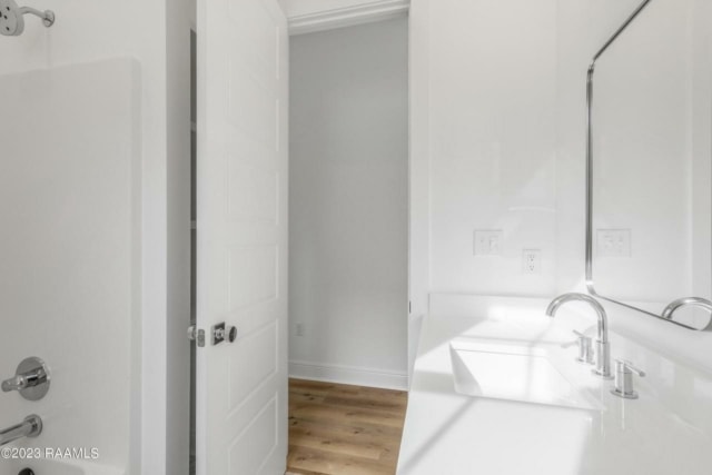 a white bathroom with wood floors and a sink.