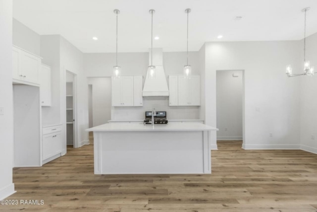 an empty kitchen with white cabinets and hardwood floors.