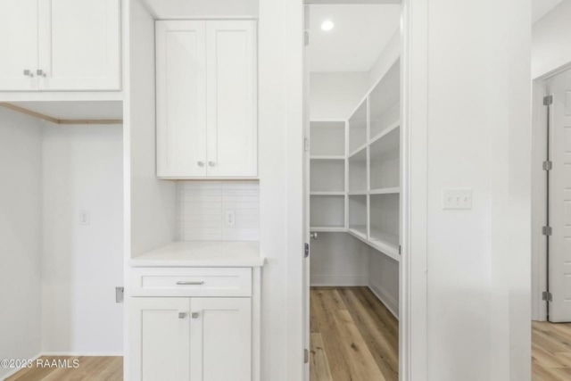 a white kitchen with white cabinets and wood floors.