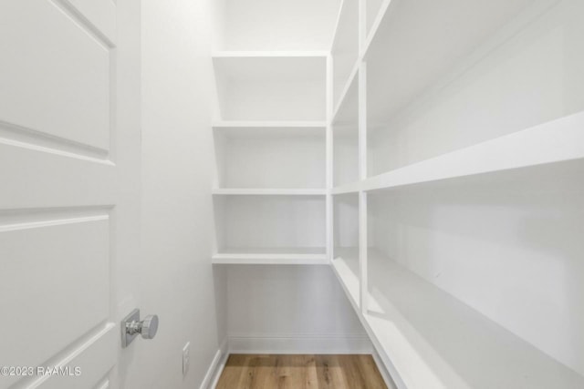 a white closet with shelves and a wooden floor.
