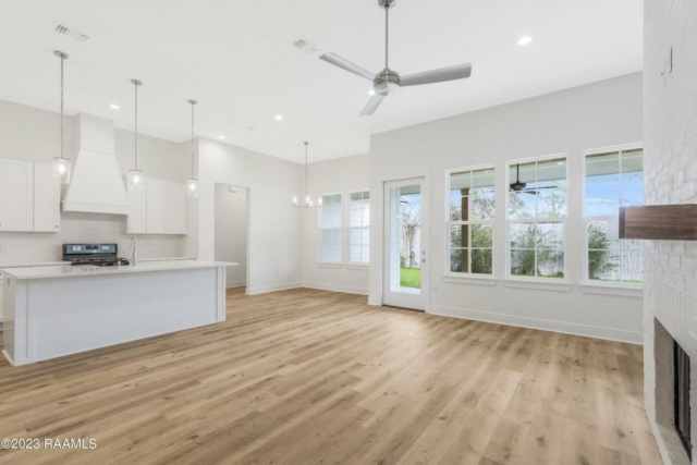 an empty kitchen with wood floors and a ceiling fan.
