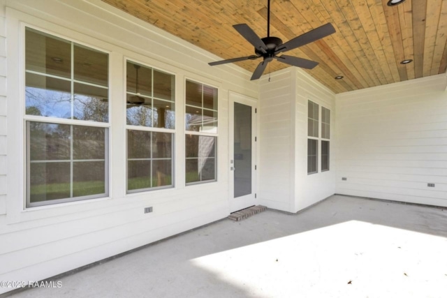 a porch with a ceiling fan and white siding.