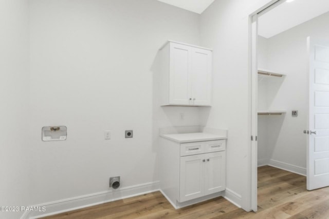 an empty room with white cabinets and wood floors.