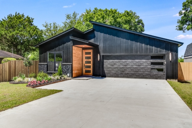 a modern home with black siding and a garage.