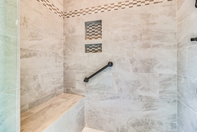 a shower with a bench and tiled walls.