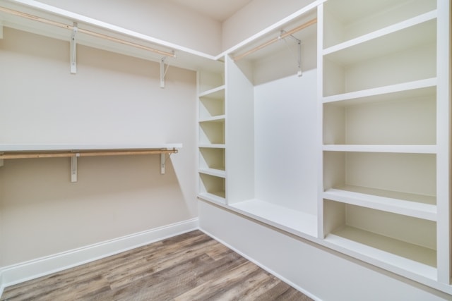 a walk in closet with shelves and a wooden floor.