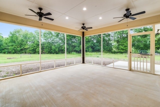 a screened in porch with ceiling fans and a view of a field.
