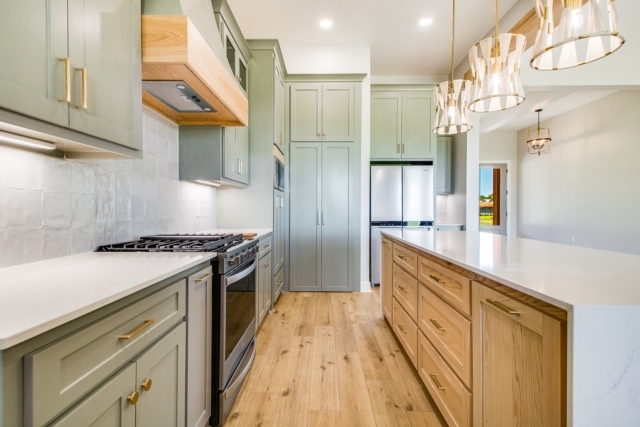 a kitchen with green cabinets and wood floors.