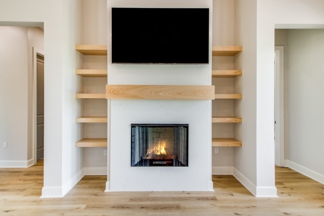 a fireplace with shelves and a tv above it.