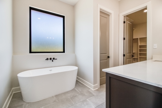 a white bathroom with a tub and window.