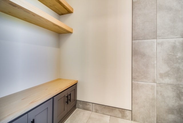 a small bathroom with a wooden bench and shelves.
