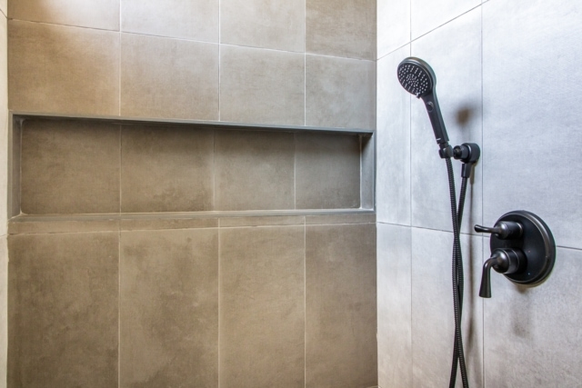 a tiled shower with a hand held shower head.