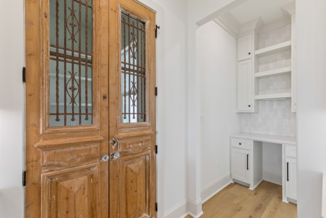 a hallway with a wooden door and white walls.