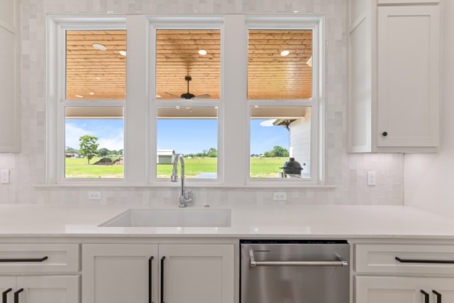 a kitchen with white cabinets and a window.