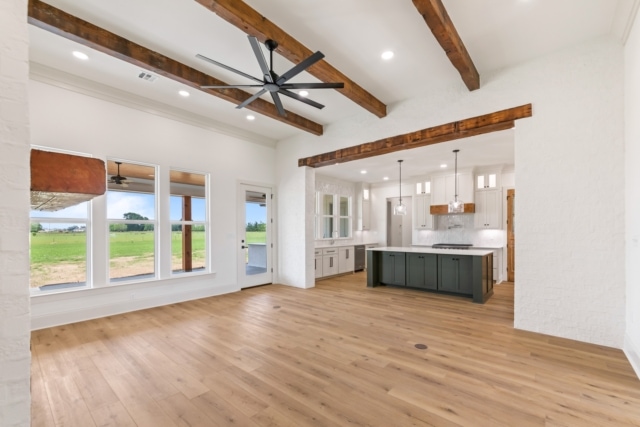 an empty kitchen with wood beams and a ceiling fan.