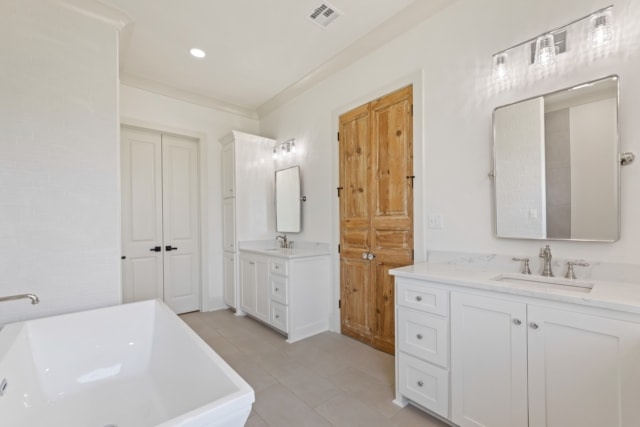 a white bathroom with wooden cabinets and a bathtub.