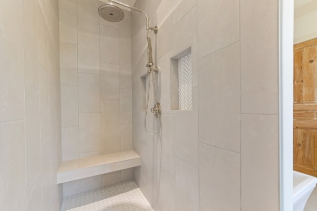a white tiled shower with a wooden bench.