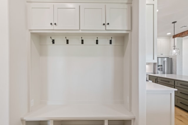 a white mudroom with a bench and storage.