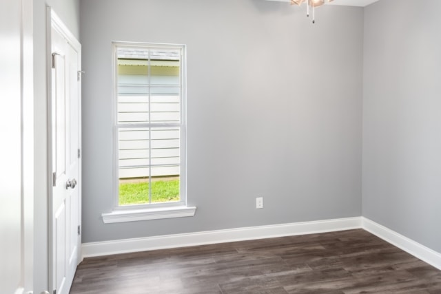 an empty room with gray walls and hardwood floors.