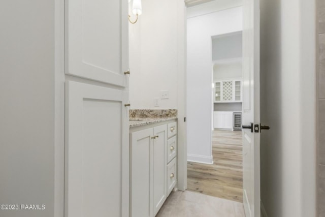 a bathroom with white cabinets and hardwood floors.