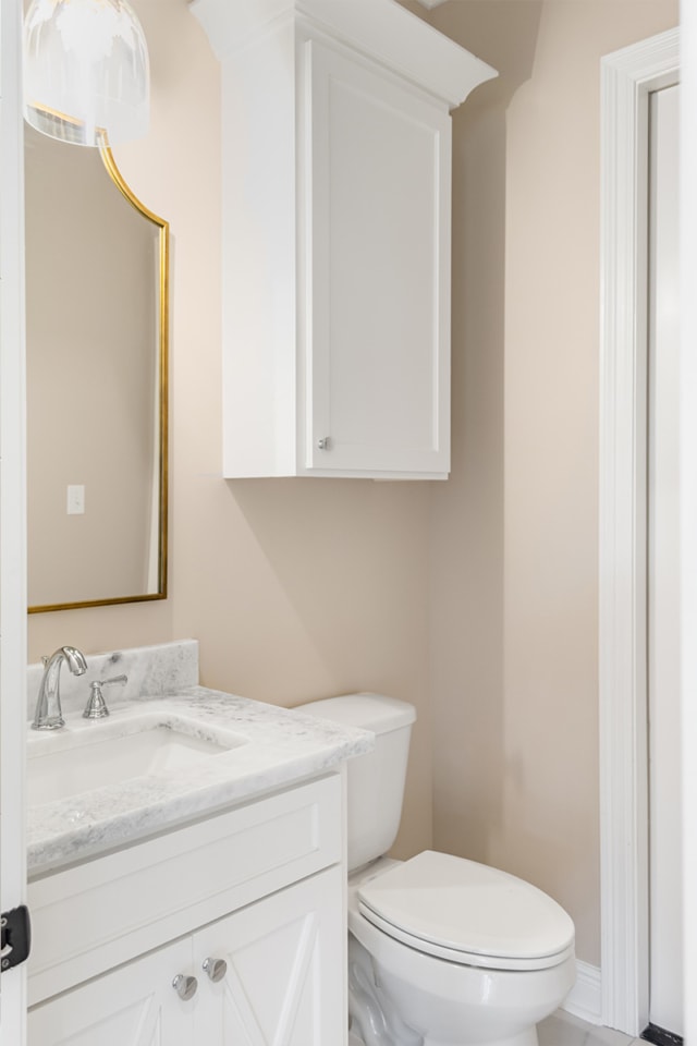 a bathroom with white cabinets and a gold mirror.