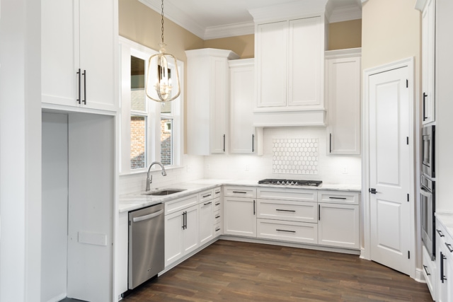 a kitchen with white cabinets and wood floors.