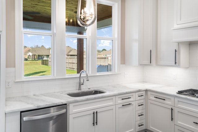 a white kitchen with a sink and a window.