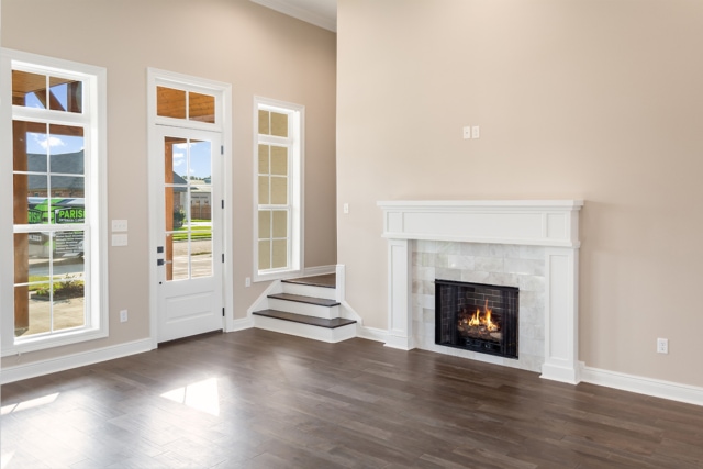 an empty living room with hardwood floors and a fireplace.