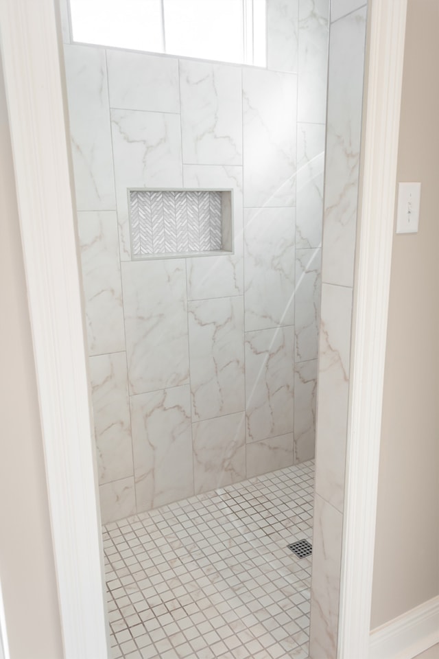 a white tiled shower with a glass door.