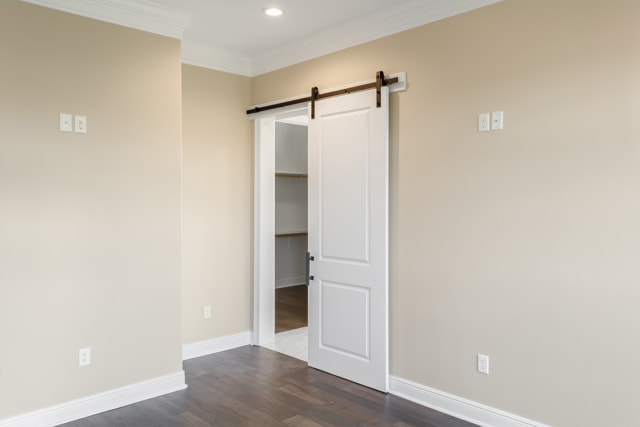 a room with a white door and hardwood floors.