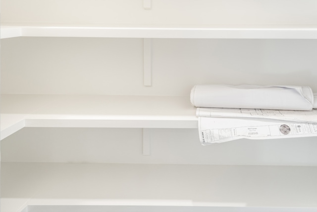 a white closet with paper on the shelves.