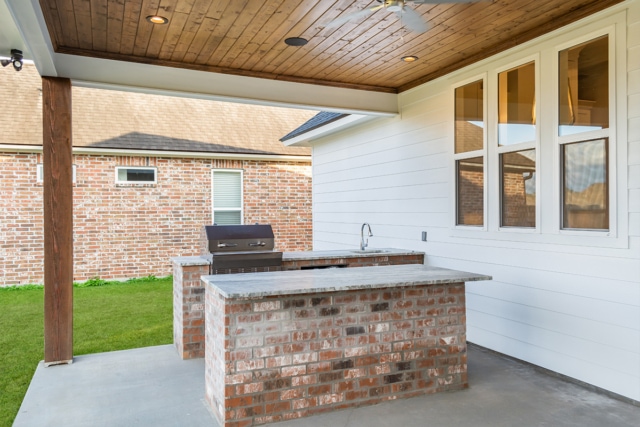 an outdoor kitchen with a brick counter top and a ceiling fan.