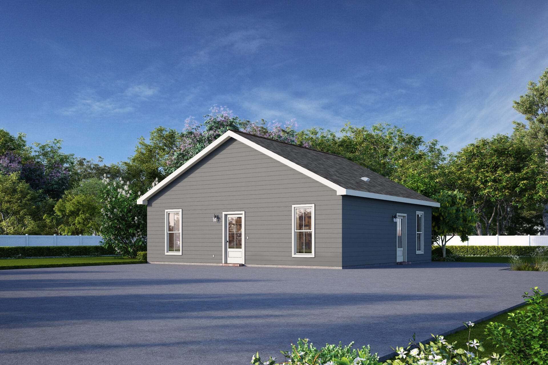 A single-story gray house with white trim sits on a large paved area, surrounded by green trees and a white fence under a blue sky.