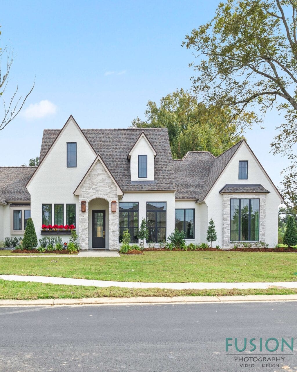 Two-story suburban house with a white stucco exterior, stone accents, and a shingled roof.